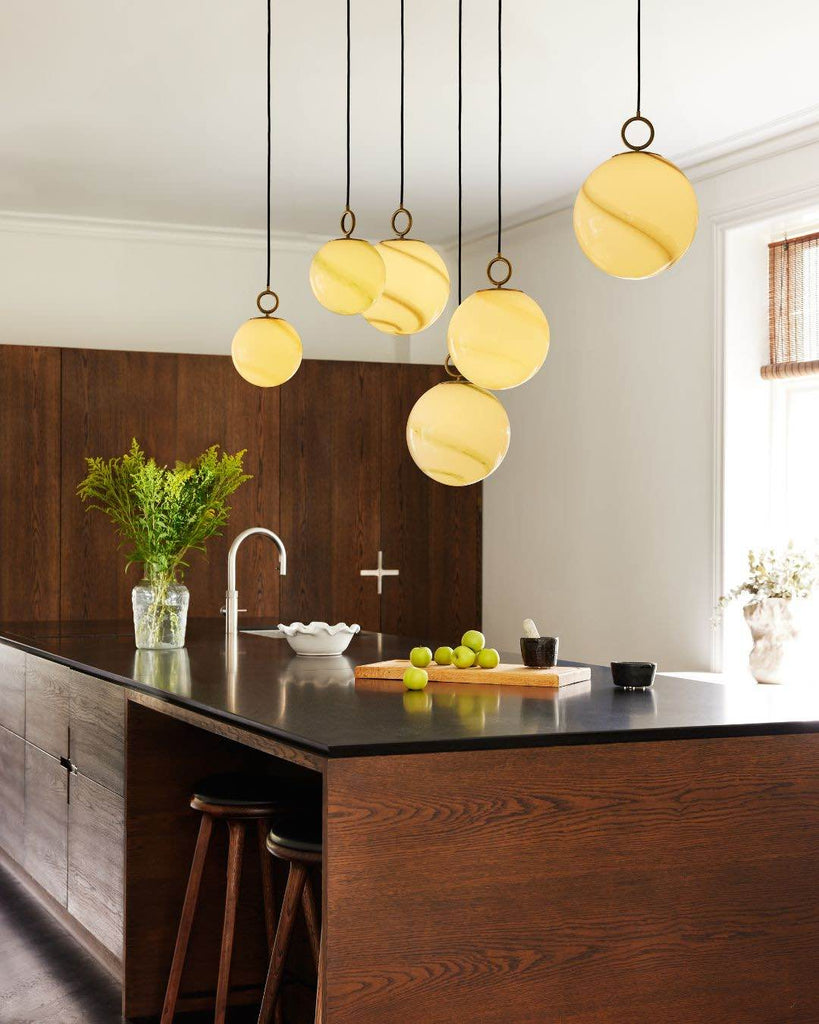 Modern kitchen with pendant lights, wooden island, and black countertop.