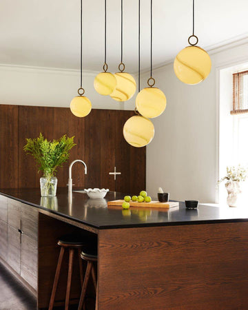 Modern kitchen with pendant lights, wooden island, and black countertop.